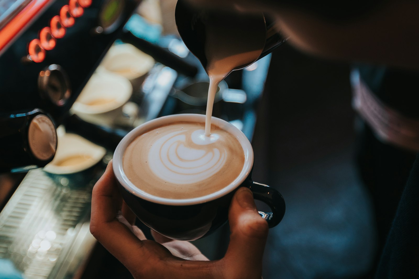 Barista pouring latte art into a cup at The Coffee Stop